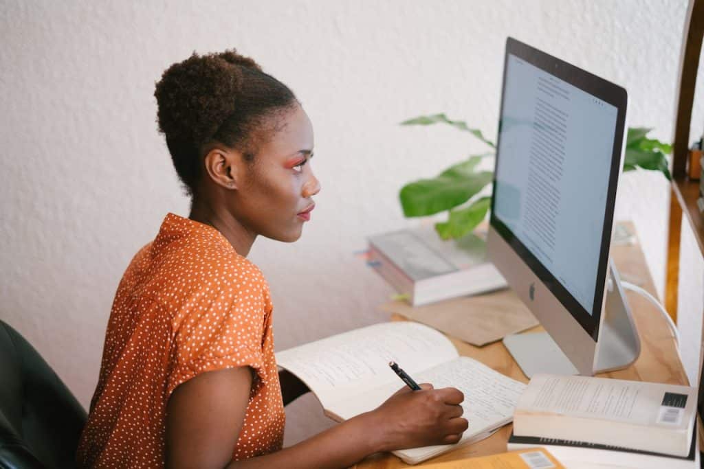 Data analyst studying using a book and computer. 