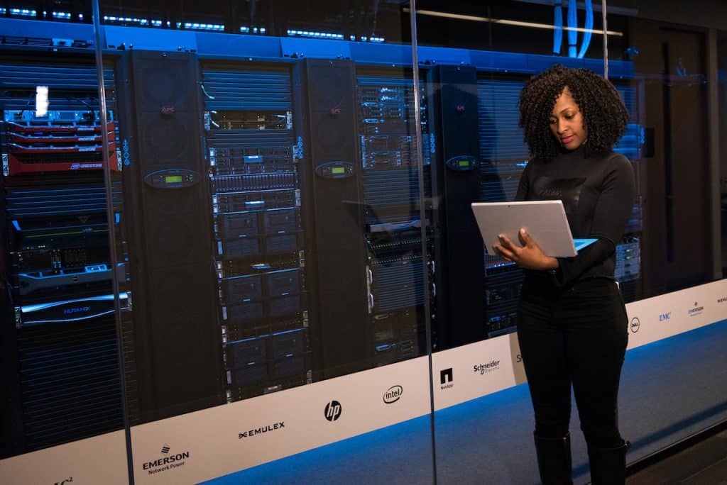 A female data scientist standing next to server racks.